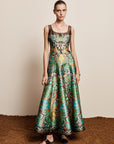 Woman wearing the ALEMAIS sustainable Charlotte Gown, a flowing maxi-length dress featuring intricate floral print details and draped long sleeves.. LUXAMORE