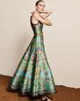 Woman wearing the ALEMAIS sustainable Charlotte Gown, a flowing maxi-length dress featuring intricate floral print details and draped long sleeves.. LUXAMORE