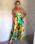 alemais colorful dress worn by mature model standing against a concrete wall.