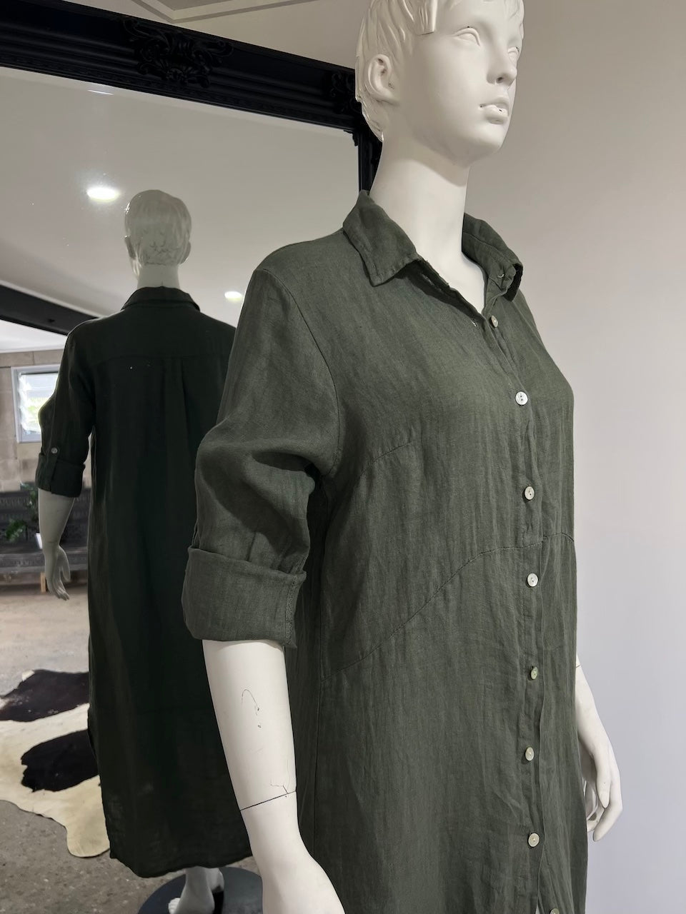 Mannequin wearing a dark green dress in a store setting