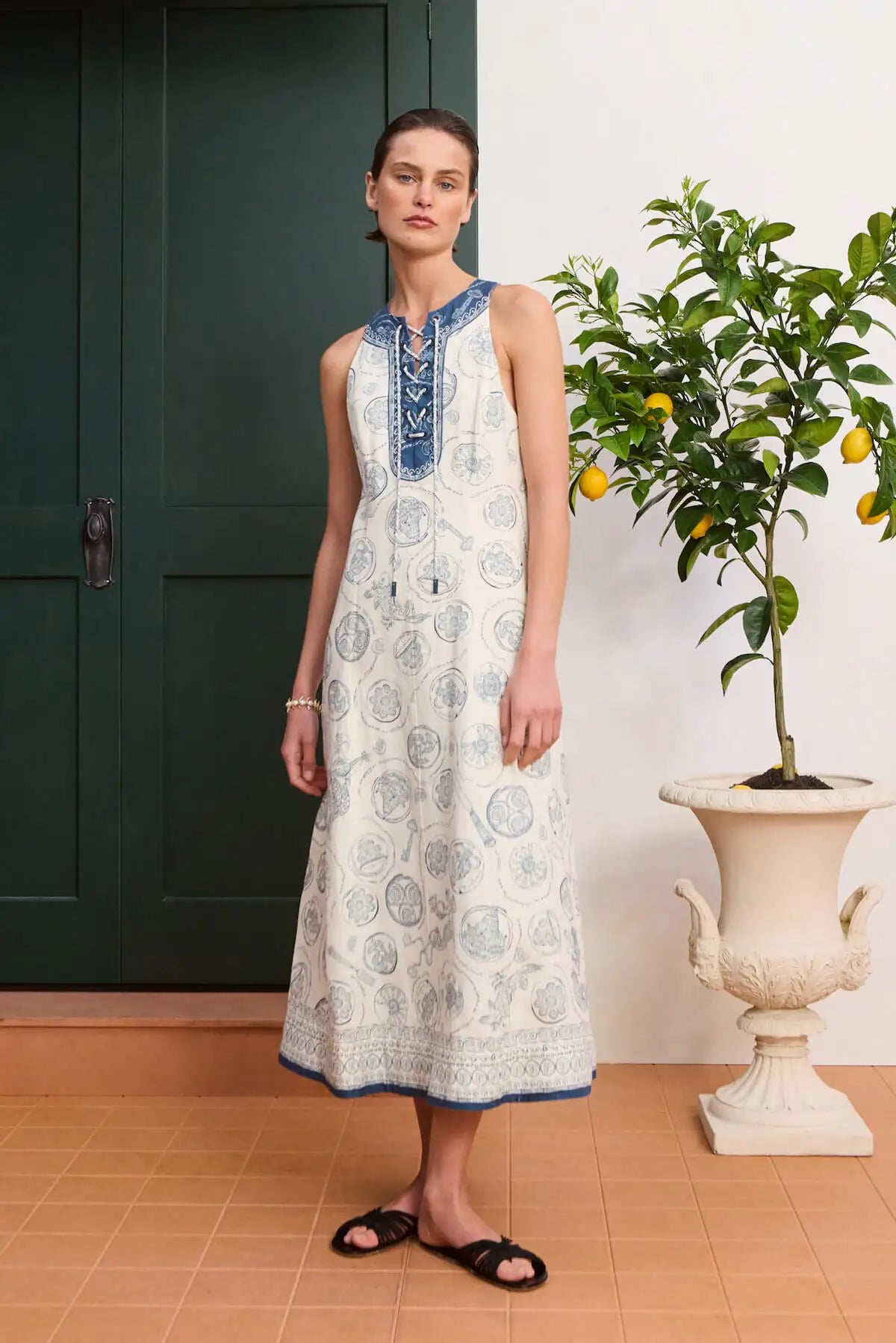 Sleeveless white linen dress: ALÉMAIS Lucky Lace Up Midi Dress in ivory featuring a high round neck with collar tie details. LUXAMORE