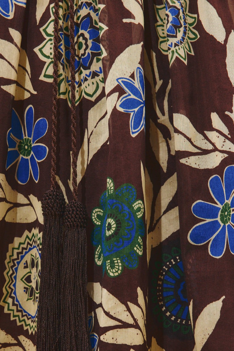 Alemais_Jasper_Shirtdress  Close-up of a patterned fabric with blue flowers and geometric shapes on a brown background.